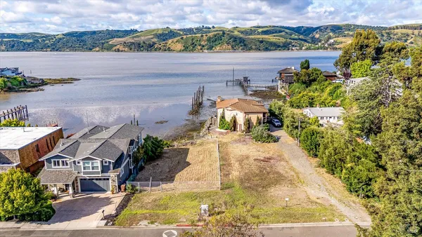an aerial view of a house with a yard and ocean view