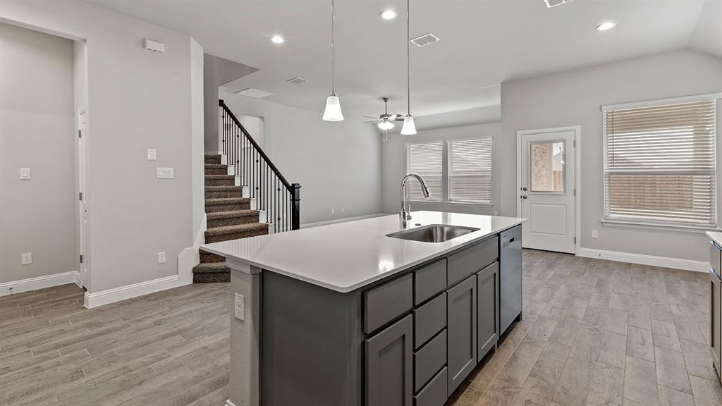 729 Soaring Hawk Drive Aledo, TX 76008 - Photo 4 of 38 a kitchen that has a sink a microwave oven a stove and white cabinets with wooden floor