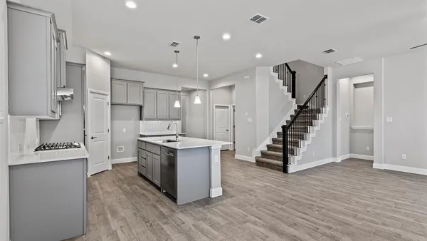 a kitchen that has a sink a microwave oven a stove and white cabinets with wooden floor