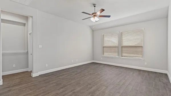 an empty room with wooden floor and windows