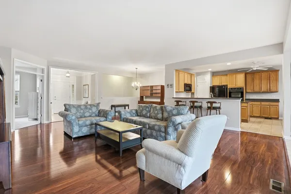 a living room with couches and kitchen view with wooden floor
