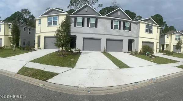 a view of a white house with a yard and large parking space