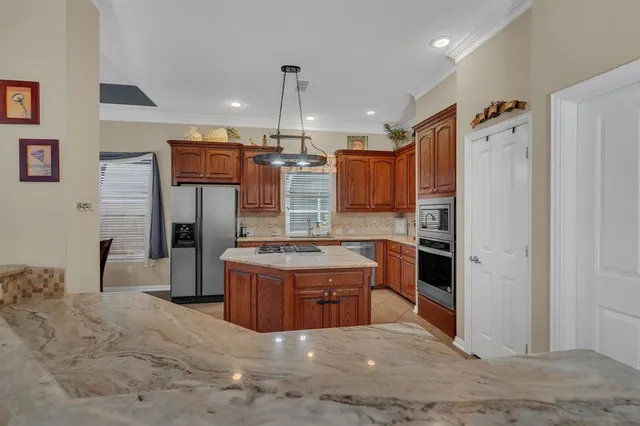a kitchen with granite countertop a refrigerator and a stove top oven
