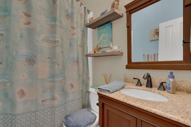 a bathroom with a granite countertop sink a toilet and shower