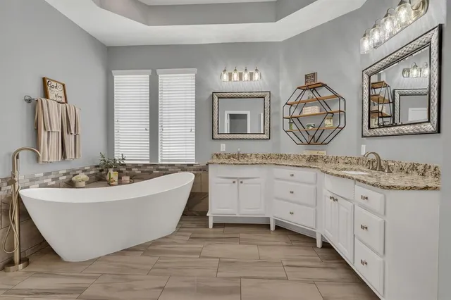 a spacious bathroom with a tub sink and mirror