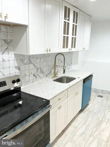 a kitchen with granite countertop a sink dishwasher a stove and white cabinets