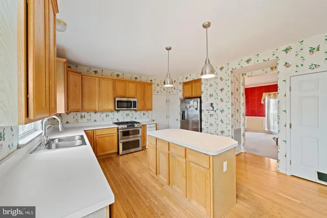 a large kitchen with stainless steel appliances granite countertop a sink dishwasher a stove and a dining table with wooden floor