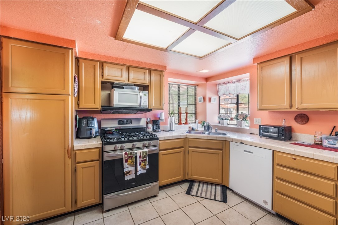 6513 Deadwood Road Las Vegas, NV 89108 - Photo 16 of 34 Kitchen with white appliances, light tile patterned floors, and a textured ceiling