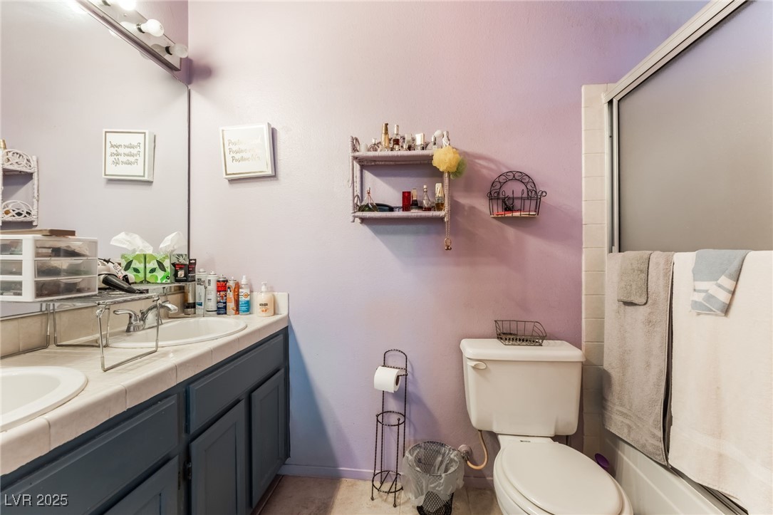 6513 Deadwood Road Las Vegas, NV 89108 - Photo 23 of 34 Full bath featuring double vanity, enclosed tub / shower combo, and light tile patterned floors