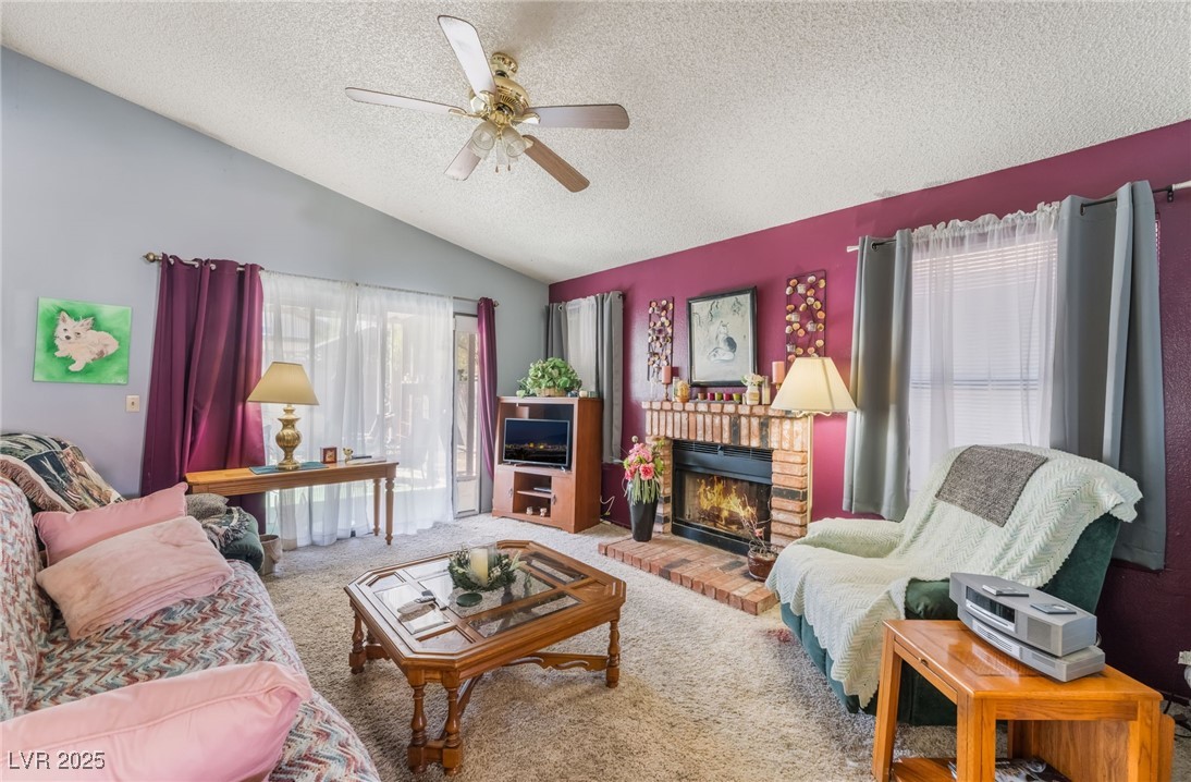 6513 Deadwood Road Las Vegas, NV 89108 - Photo 6 of 34 Carpeted living area with a textured ceiling, lofted ceiling, a brick fireplace, and ceiling fan