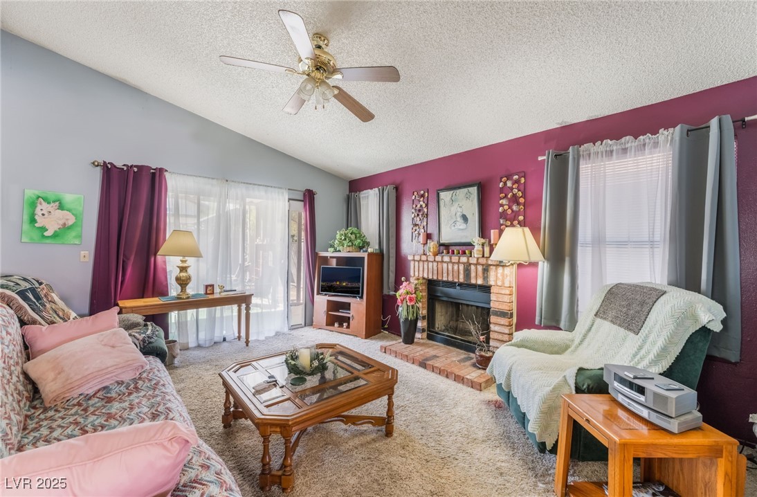 6513 Deadwood Road Las Vegas, NV 89108 - Photo 7 of 34 Living room featuring a textured ceiling, vaulted ceiling, a brick fireplace, carpet, and ceiling fan