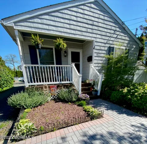 a view of a house with potted plants and a bench