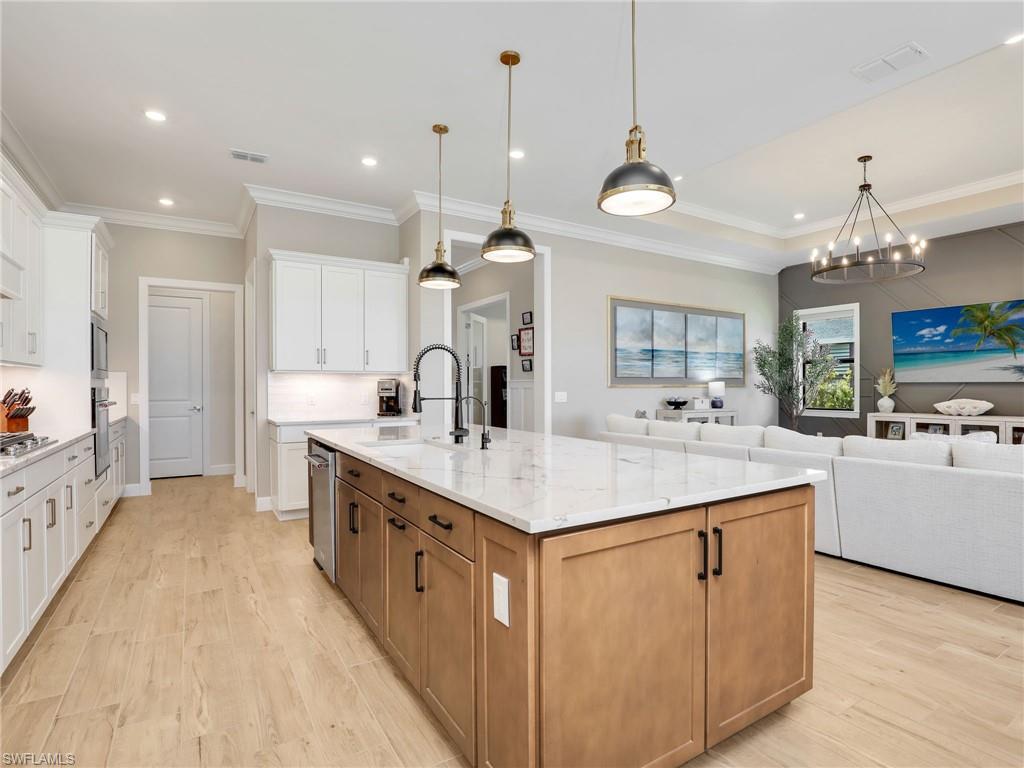 18412 Ridgeline Drive Estero, FL 33928 - Photo 15 of 50 a large kitchen with kitchen island a sink a center island a stove and a view of living room