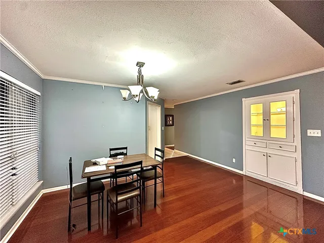 a view of a dining room with furniture a chandelier and wooden floor