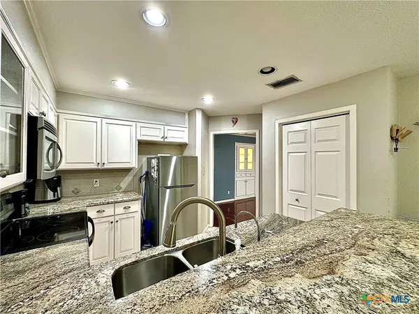 a view of a kitchen with sink refrigerator and natural light