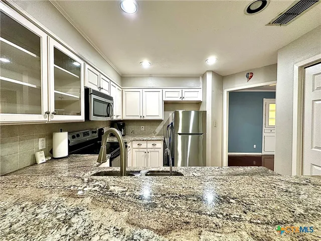 a kitchen with a refrigerator sink and cabinets