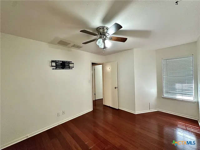 a view of an empty room with window and wooden floor