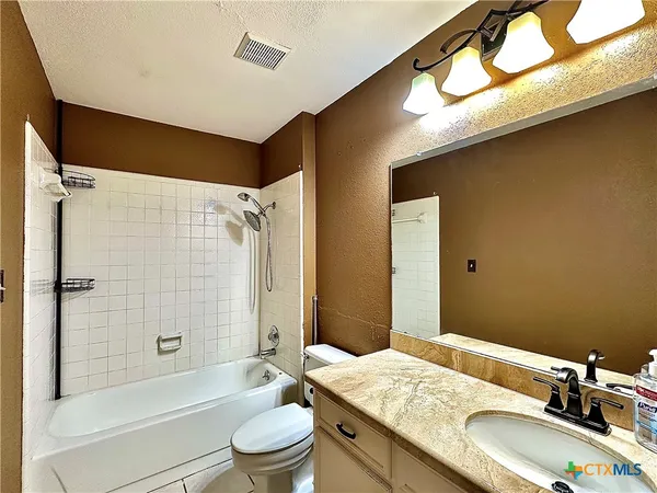 a bathroom with a granite countertop sink a toilet and shower