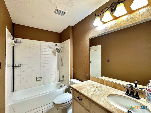 a bathroom with a granite countertop sink a toilet and shower