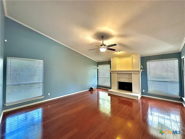 a view of an empty room with wooden floor fireplace and a window