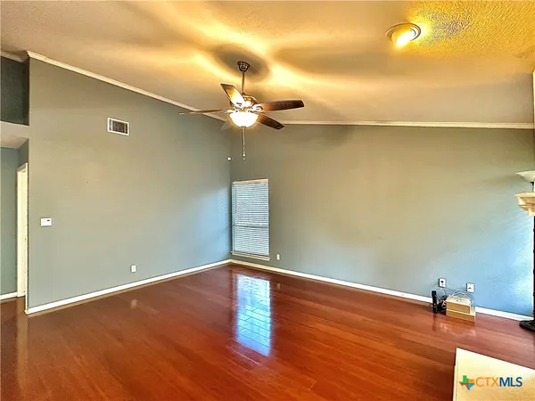 a view of a room with wooden floor and a ceiling fan