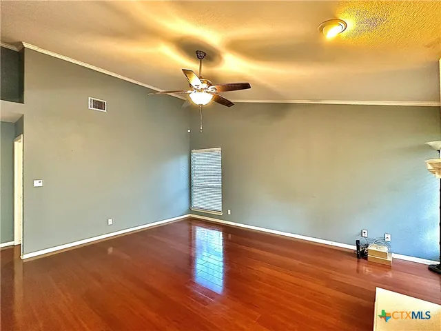 a view of a room with wooden floor and a ceiling fan