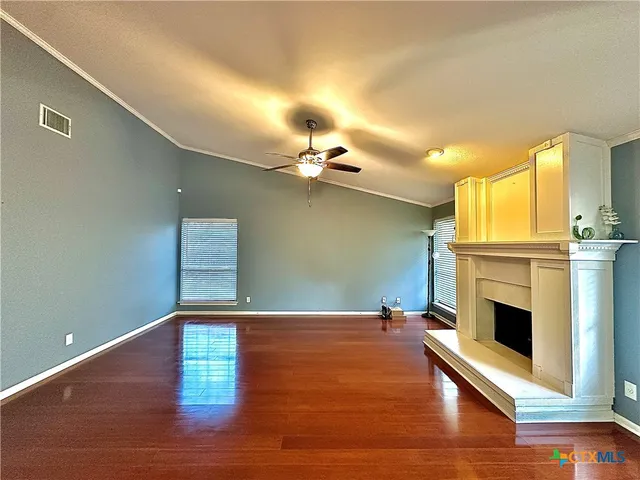 a view of a livingroom with a fireplace a ceiling fan and wooden floor
