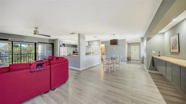 a large living room with stainless steel appliances granite countertop a couch wooden floor and a large window