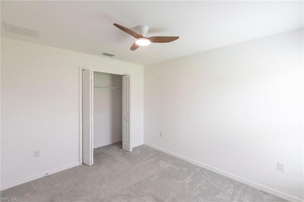 358 Pembroke Street Lehigh Acres, FL 33974 - Photo 21 of 45 an empty room with a ceiling fan and carpet