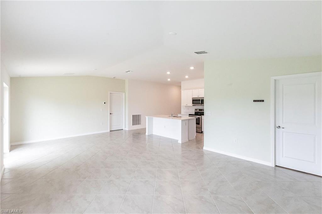 358 Pembroke Street Lehigh Acres, FL 33974 - Photo 6 of 45 an empty room with kitchen view and a refrigerator