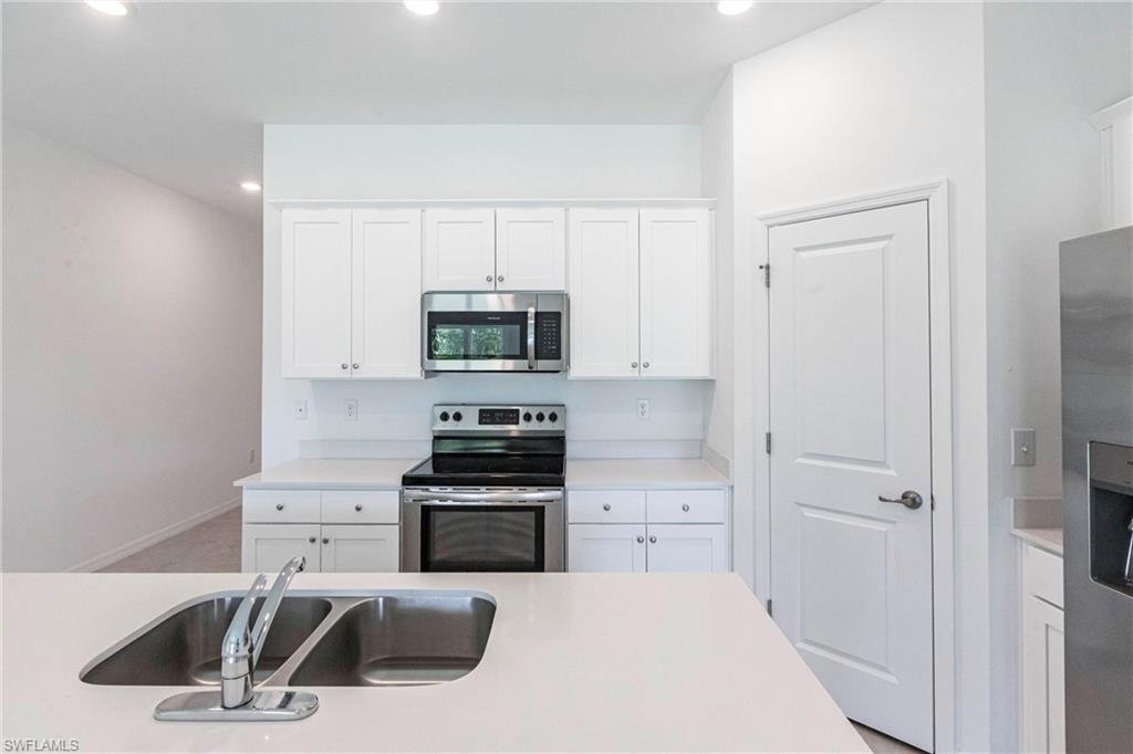 358 Pembroke Street Lehigh Acres, FL 33974 - Photo 10 of 45 a kitchen with white cabinets and appliances