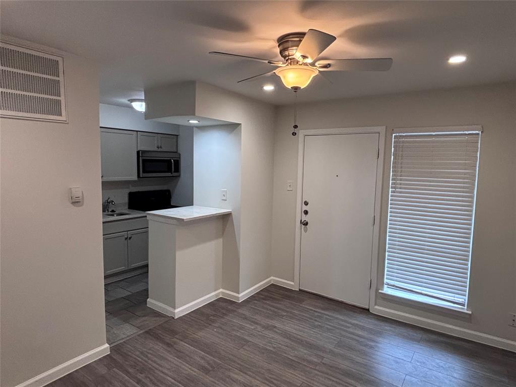 4300 Congress Avenue, Unit 216 Dallas, TX 75219 - Photo 3 of 13 an empty room with wooden floor a ceiling fan and window