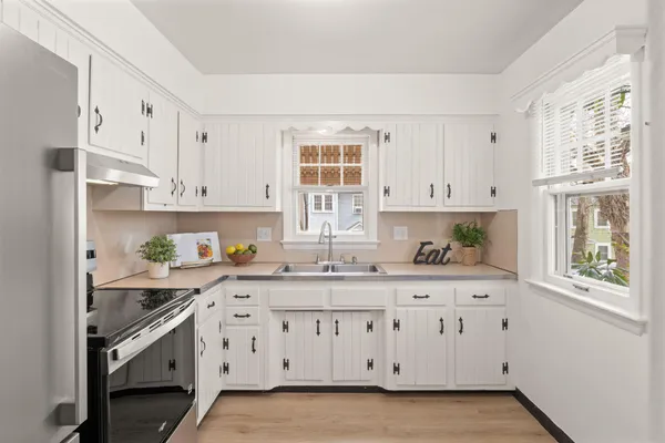a kitchen with stainless steel appliances white cabinets a stove a sink and a window