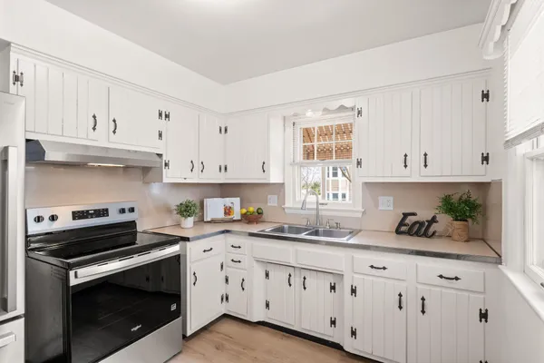 a kitchen with granite countertop white cabinets and stainless steel appliances