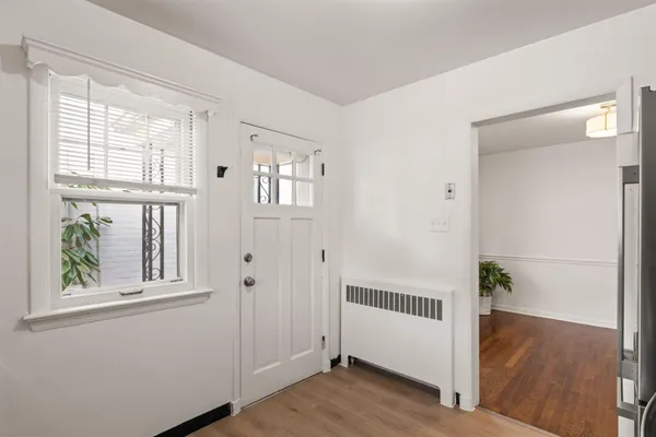 a view of a hallway with windows and entryway with wooden floor