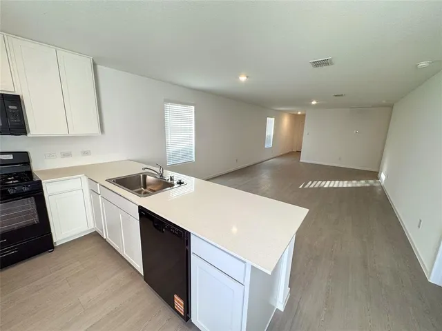 a kitchen with a sink a stove a refrigerator and white cabinets