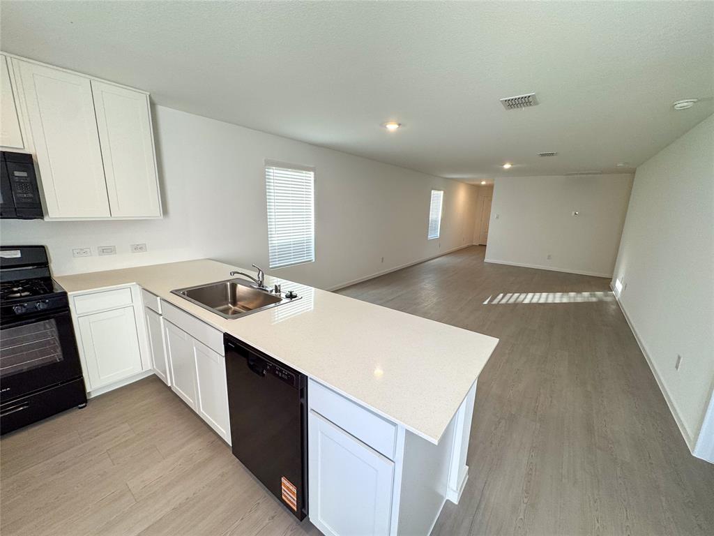 3915 Selawik Street Sherman, TX 75090 - Photo 4 of 19 a kitchen with a sink a stove a refrigerator and white cabinets