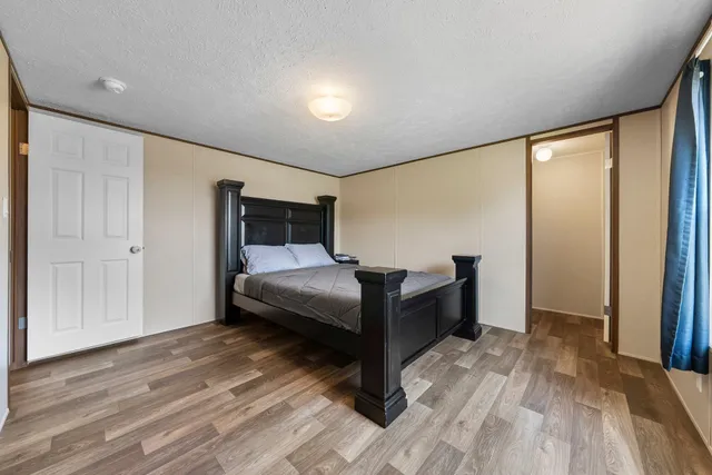 a bedroom with a bed and a dresser with wooden floor
