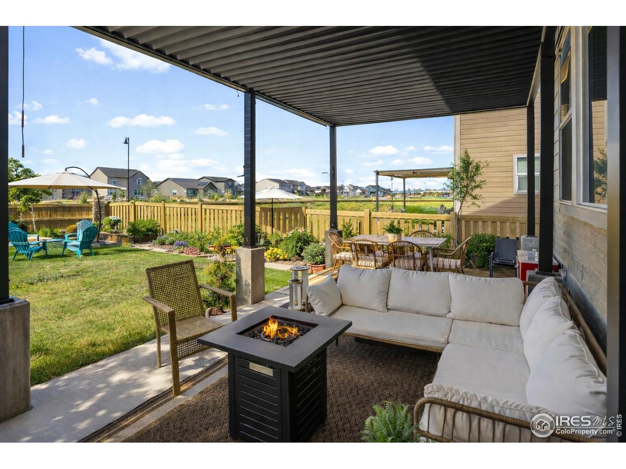 5247 Alberta Falls Street Timnath, CO 80547 - Photo 30 of 43 Covered patio with pergola, outdoor seating, and fire pit, opening to a fenced yard with natural summer lawn and garden beds-ideal for relaxed outdoor living and entertaining