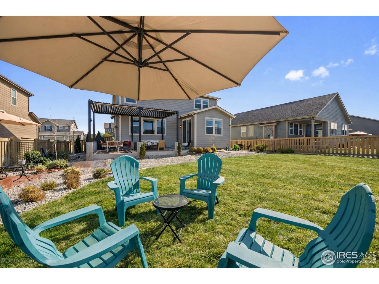 5247 Alberta Falls Street Timnath, CO 80547 - Photo 33 of 43 Sunny backyard gathering space with umbrella-shaded seating, open lawn, and room to relax or entertain on warm summer days