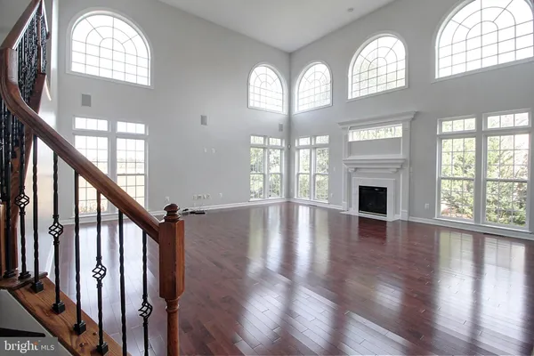 an empty room with wooden floor fan and a fireplace