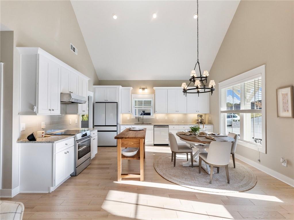 232 Campbell Street Cleveland, GA 30528 - Photo 6 of 37 a kitchen with stainless steel appliances kitchen island granite countertop a stove top oven a sink a dining table and chairs with wooden floor