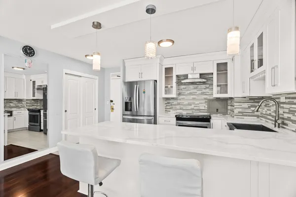 a kitchen with stainless steel appliances kitchen island granite countertop a stove and white cabinets