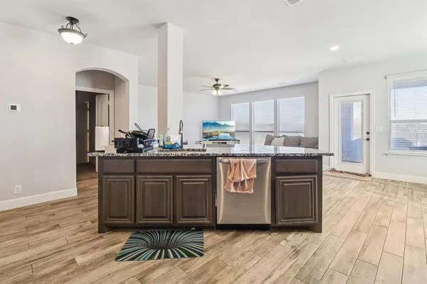 a kitchen with stainless steel appliances granite countertop a stove a sink dishwasher and a refrigerator with wooden floor