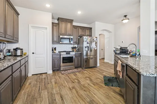 a kitchen with stainless steel appliances granite countertop a refrigerator a stove and a sink