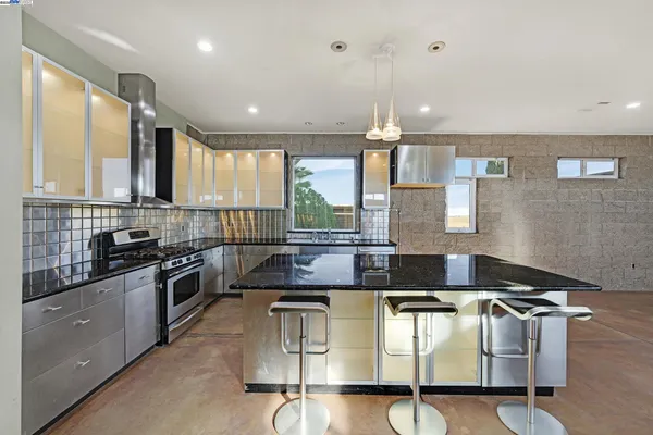 a kitchen with granite countertop a stove a sink a counter space and cabinets