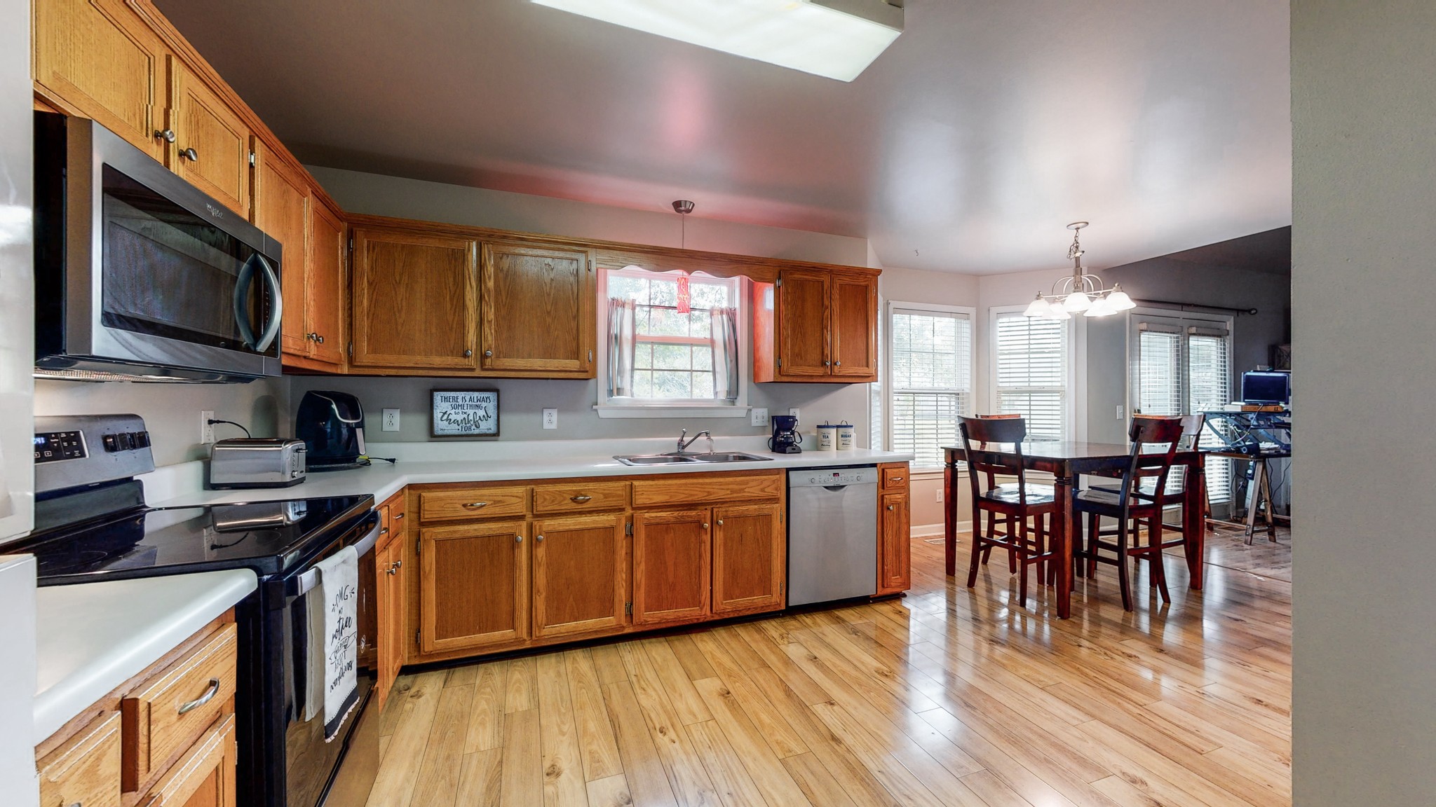 2804 Rippavilla Way Spring Hill, TN 37174 - Photo 5 of 18 a kitchen with stainless steel appliances granite countertop wooden floors a stove a microwave a sink a dining table and chairs