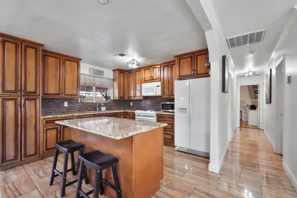 a kitchen with stainless steel appliances granite countertop a refrigerator a sink dishwasher and white cabinets with wooden floor