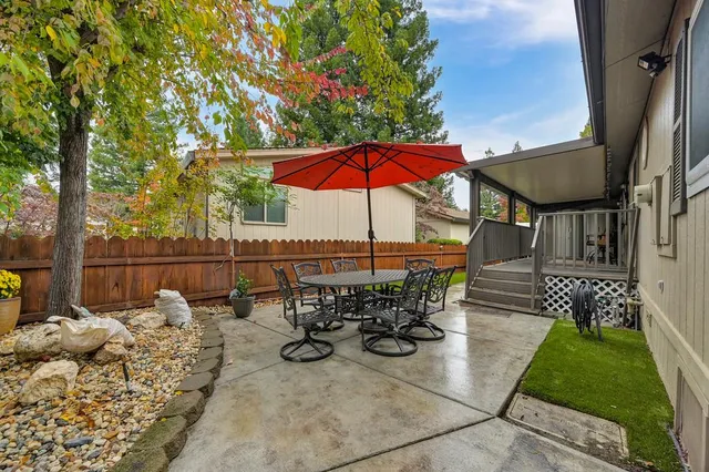 a view of a patio with couches table and chairs under an umbrella with a small yard