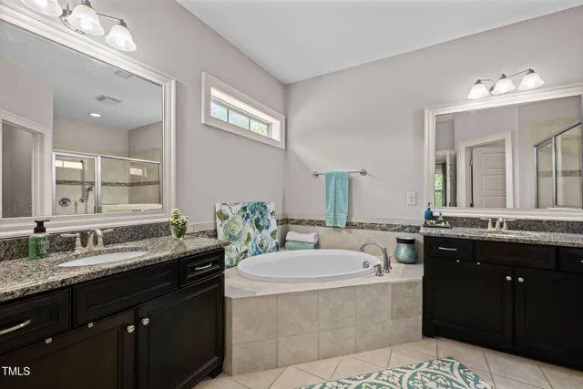 a bathroom with a granite countertop double vanity sink a mirror and a bathtub